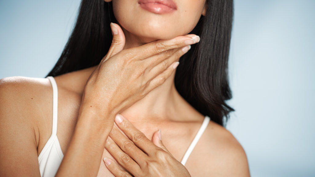 Close up of a woman touching her neck and jawline, highlighting biostimulators treatment concepts.