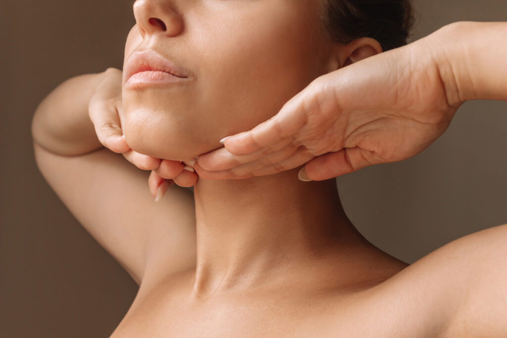 A woman touching her chin and jawline highlighting facial contouring, skin tightening and asethetic beauty treatments