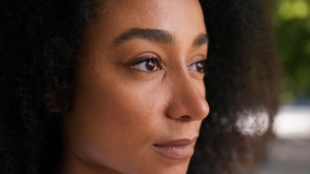 Close up potrait of women with Natural texted hair and glowing skin, highlighting beauty and skincare.