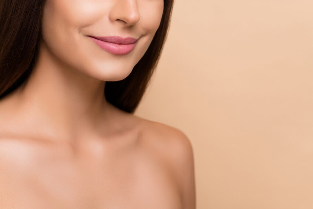 beauty potrait of a smiling woman with glowing skin and soft pink lips